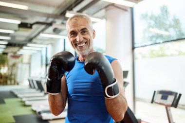 Happy mature man exercises boxing while working out at gym and l