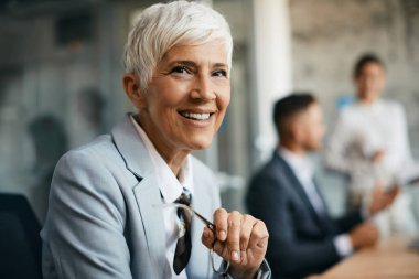 Portrait of happy mature CEO working in her office and looking at camera.