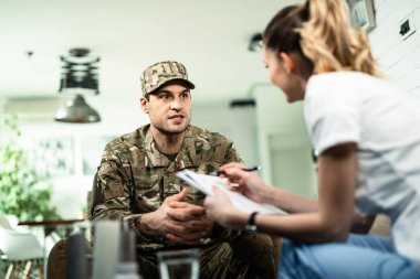 Young military man talking to healthcare worker who is visiting him at home. 