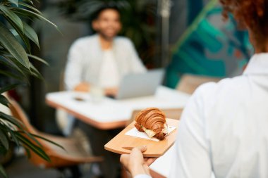 Close-up of waitress serving sandwich in a cafe.