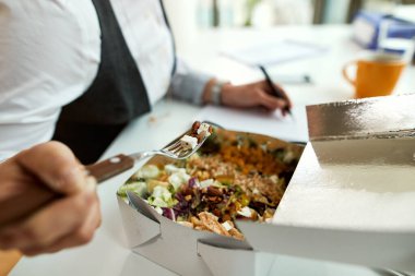 Close-up of businesswoman having healthy lunch while working in the office. 