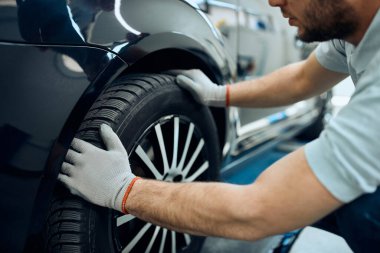 Close-up of mechanic changing car tire at auto repair shop. 