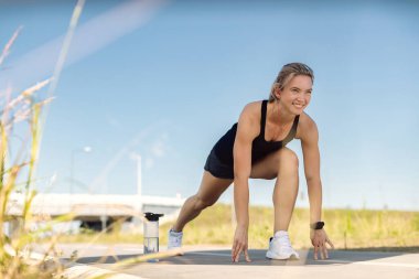 Happy athletic woman doing stretching exercises while having sports training outdoors. 