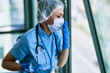 Female doctor coughing while working at medical clinic during COVID-19 pandemic. 