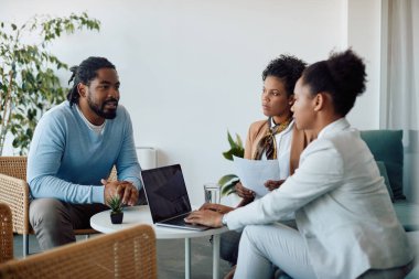 Young black man having job interview and talking to female members of human resource team during the meeting. 