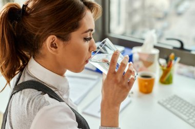 Young businesswoman drinking water while working in the office.
