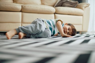 Smiling little boy relaxing on the floor at home and looking at camera. 