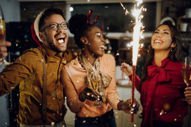 Small group of carefree friends drinking Champagne and having fun on New Year's party at home. 