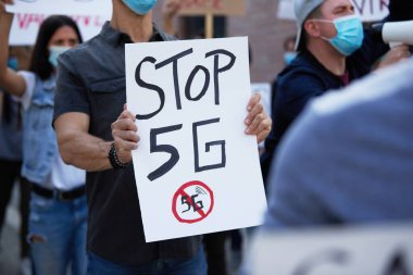 Unrecognizable man carrying banner with 'stop 5G' inscription on public demonstrations. 