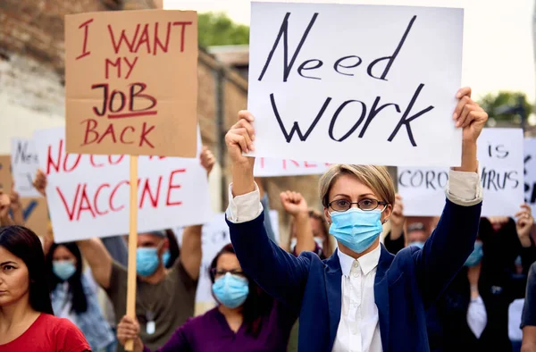 Crowd of people wearing protective face mask and protesting after losing their job due to coronavirus pandemic.