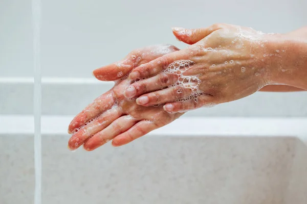Close-up of woman cleaning hands with soap in the bathroom.
