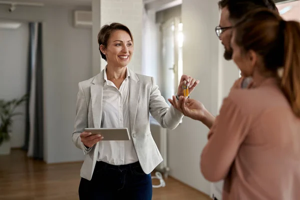 Young Happy Real Estate Agent Giving House Keys Couple Who — Foto Stock