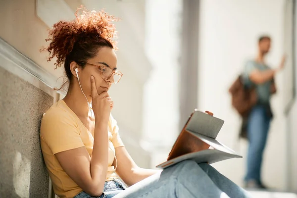 Young woman learning while using touchpad at university hallway.