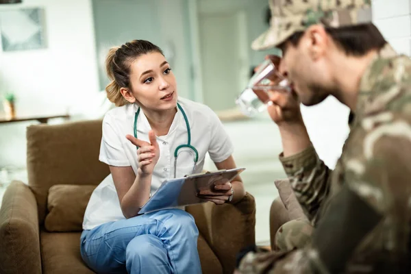 Female healthcare worker communicating with military officer while analyzing his medical reports at home.