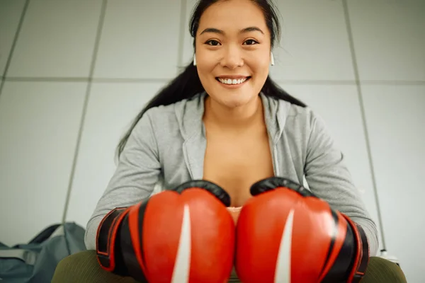 Happy Asian Sportswoman Wearing Boxing Gloves While Sitting Gym Dressing — Foto de Stock