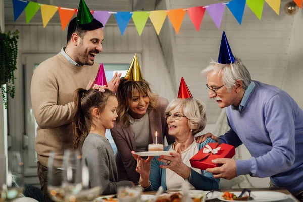 Happy Senior Woman Holding Birthday Cake While Celebrating Her Family — стоковое фото