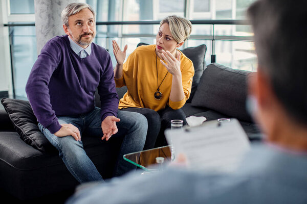 Mid adult couple with relationship difficulties having counseling with a therapist.