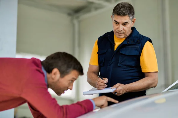 Auto Repair Man Writing Notes While His Customer Pointing Problematic — ストック写真