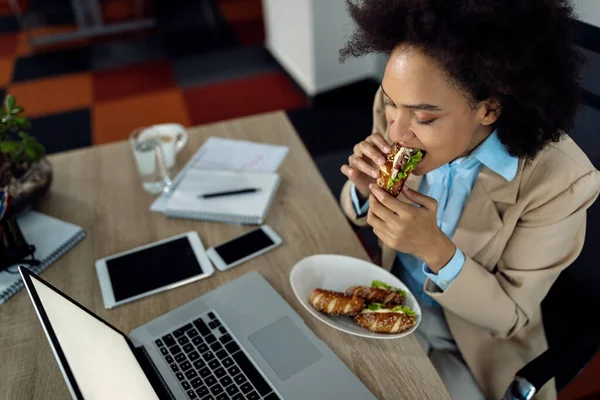 High Angle View Black Businesswoman Eating Sandwich While Using Laptop — Φωτογραφία Αρχείου