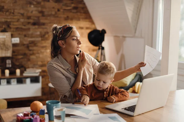 Working Mother Communicating Smart Phone Examining Reports While Son Sitting — Φωτογραφία Αρχείου