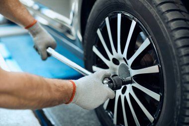 Close-up of mechanic changing car tire at auto repair shop. 