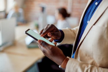 Close-up of African American businessman using mobile phone while working in the office.