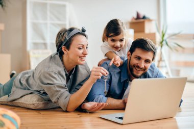 Happy family using laptop and having video call after moving into new home. 