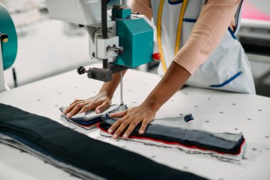 Close-up of seamstress using fabric machine while cutting fabric. 