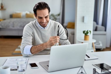 Happy businessman using computer while working at home. 
