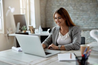 Young happy businesswoman using computer while working in the office. 