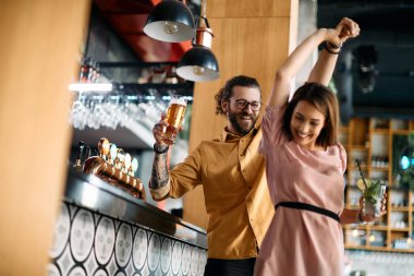 Low angle view of happy couple dancing and having fun together in a pub. 