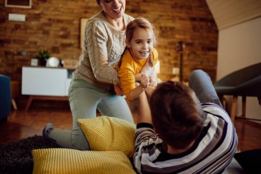 Happy family having fun together while playing at home. Focus is on small girl looking at camera.