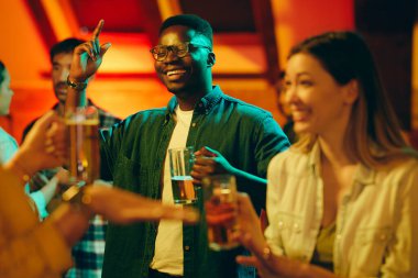 Genç mutlu siyah adam bira içiyor ve arkadaşlarıyla bir barda eğleniyor.. 