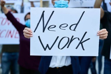 Unrecognizable businesswoman protesting against unemployment and holding banner with need work inscription. 