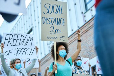 Low angle view of African American woman with raised fist participating in demonstrations during coronavirus epidemic. 