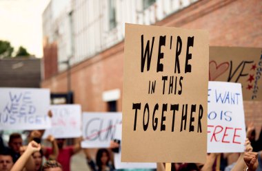 Unrecognizable person holding a placard with We are in this together inscription during public demonstrations.