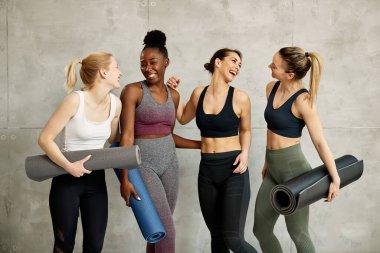 Group of young diverse sportswomen having fun and laughing against the wall at health club. 