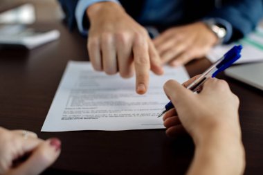 Close-up of financial advisor pointing at place of signature on a contract while closing a deal with a client.