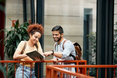 Young happy student and his female friend cooperating while studying together at the university. 