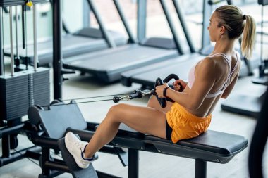 Young athletic woman having sports training on rowing machine in a gym. 