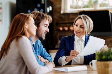 Gülümseyen sigortacı ve genç çift bir toplantıda mali raporlarını konuşuyorlar.. 