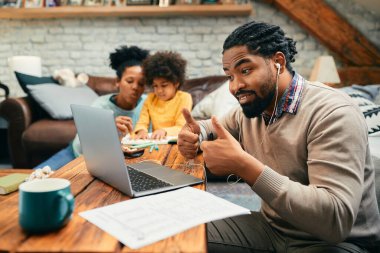Evde çalışan Afrikalı Amerikalı bir baba dizüstü bilgisayarla video görüşmesi yaparken onay veriyor.. 
