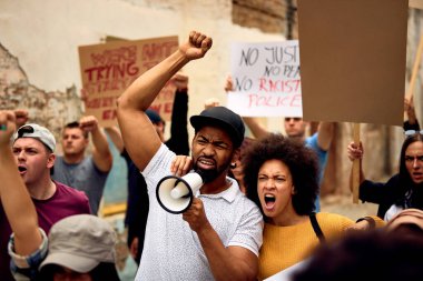 Displeased black couple shouting while marching with group of people on  anti-racism protest.