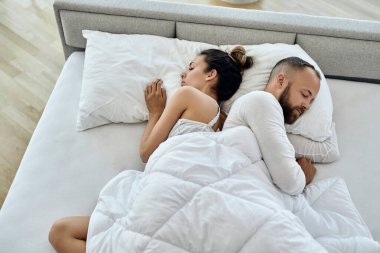 High angle view of a couple lying back to back while sleeping in the bedroom. 