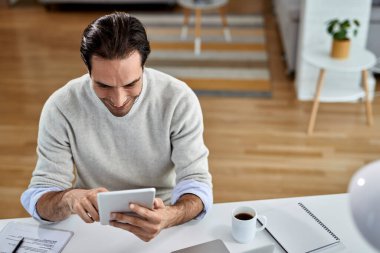 Young happy entrepreneur reading an e-mail on touchpad while working at home. 