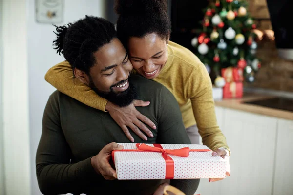 Happy Black Woman Embracing Her Husband Giving His Gift Christmas — Foto Stock
