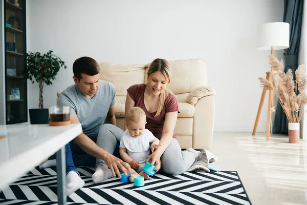 Baby boy playing with his parents on the floor in the living room.