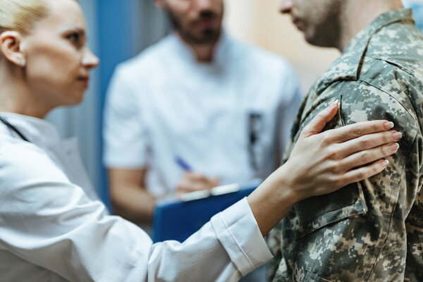 Close-up of a soldier being consoled by healthcare workers at clinic. 