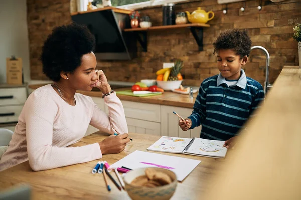 African American mother and son having fun while coloring together at home. 