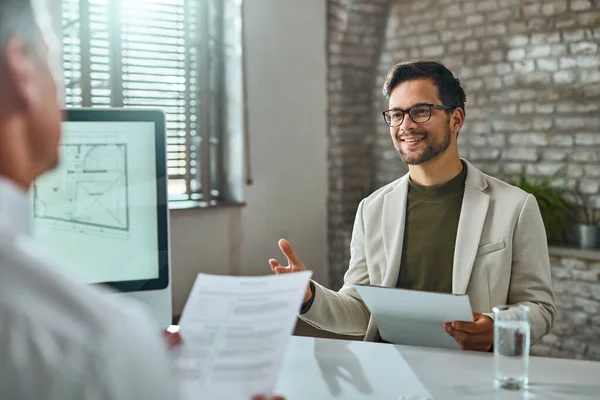 Happy male candidate talking a bout his work experience while having job interview in the office.